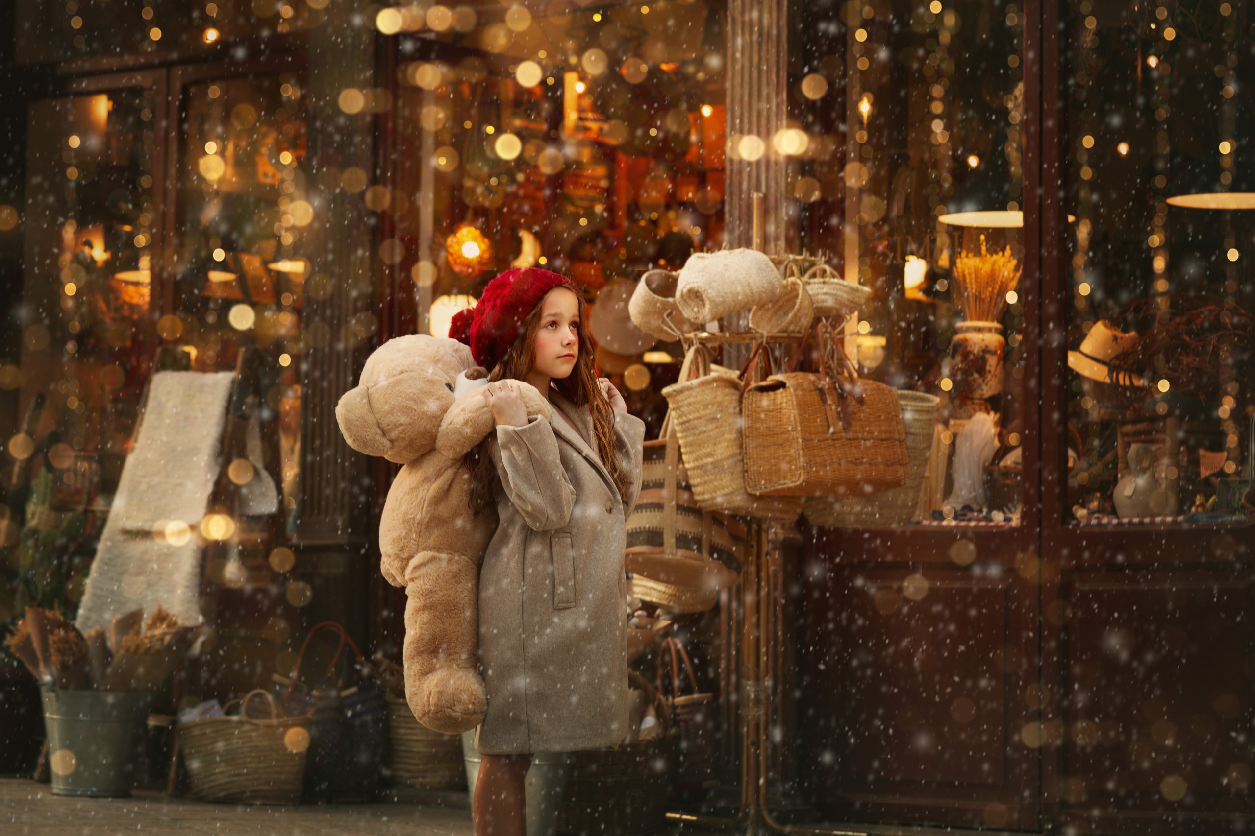 sesion-de-fotos-navidad-en-valencia-para-niños-2 niña en valencia en una foto de navidad con nieve y luces abrazando un oso gigante de peluche