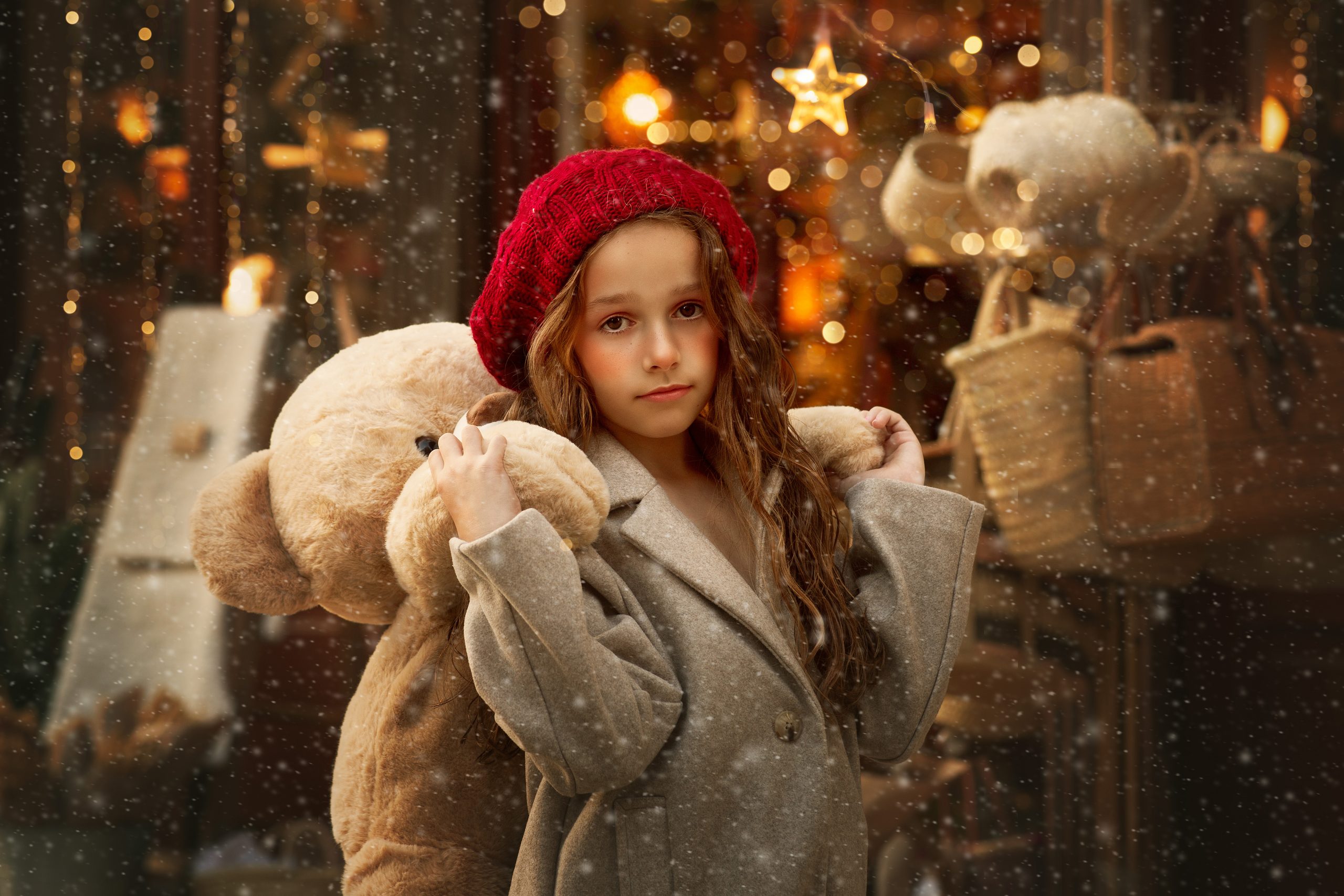 sesion-de-fotos-navidad-en-valencia-para-niños-3 niña en valencia en una foto de navidad con nieve y luces abrazando un oso gigante de peluche